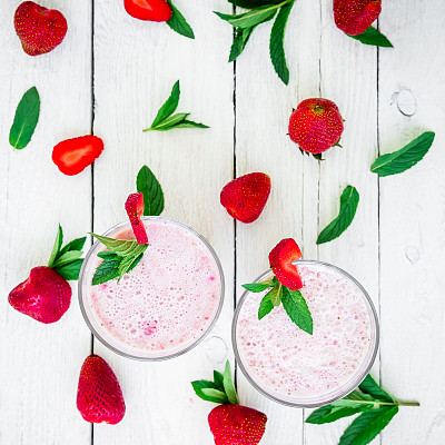 新鲜的草莓冰沙和浆果与薄荷叶在白木背景。新鲜的奶昔。平的。前视图。图片下载