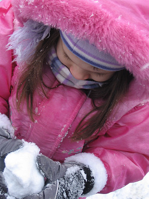 穿粉红色衣服的小女孩在堆雪球图片下载