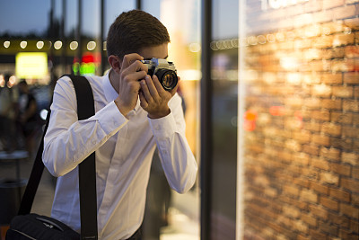 年轻的摄影师看着相机图片下载