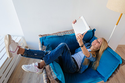 一个快乐的女孩在用平板电脑自拍。年轻的白人成功女商人坐在椅子上，手里拿着笔记本电脑在一个现代化的办公室里。图片下载
