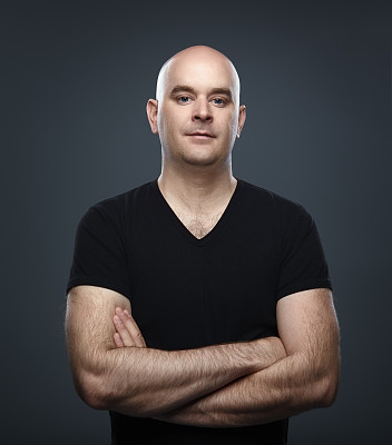 秃顶的男人穿着一件黑色t恤，双臂交叉在胸前图片下载