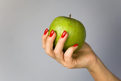 一个绿苹果在优雅的女性手中。图片下载