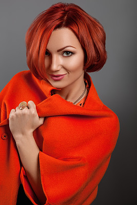 那个穿红夹克的红女孩站在墙边。图片下载