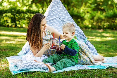 快乐的妈妈和小儿子喝果汁。生活方式和童年的概念。图片下载