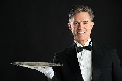 自信的侍者在燕尾服与服务托盘的肖像图片下载
