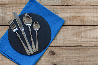 叉子，刀子和两个勺子，用餐巾放在石板上图片下载