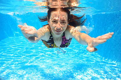 快乐微笑的女人在泳池里游泳图片下载