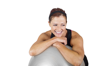 快乐健康的健身女人休息在一个运动球上图片下载