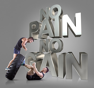 运动的年轻人在灰色背景下举起一个轮胎图片下载