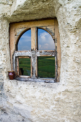 安装在岩石上的窗户，映出碧绿的田野和蔚蓝的天空图片下载