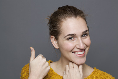 快乐的年轻女子指着一个表达自然快乐的产品图片下载