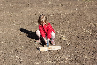 小女孩用锤子把钉子钉进木板图片下载