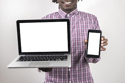年轻黑人展示空白的电脑和智能手机屏幕图片下载