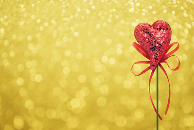红色爱心玩具与蝴蝶结在金色的背景图片下载