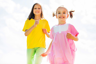 两个可爱的女孩在公园里跑步。图片下载