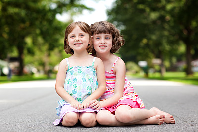 两个快乐的姐妹在街上拥抱的彩色肖像图片下载