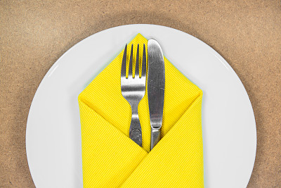 刀叉用黄色的餐巾放在白色的盘子里图片下载