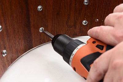 木匠用电动螺丝刀拧紧木鼓壳上的螺丝图片下载