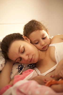 快乐的母亲躺在床上的女儿和新生儿图片下载