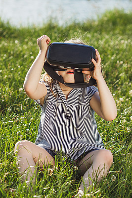小女孩戴着虚拟现实眼镜在户外玩游戏图片下载