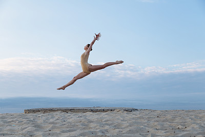 一个年轻美丽的女人穿着紧身衣在沙漠的日出跳舞图片下载
