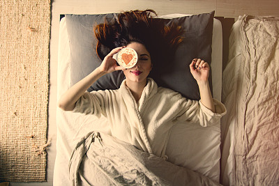 一个年轻的红发女人的肖像，喝着咖啡躺在床上图片下载