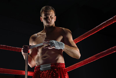 拳击手站在拳击场的角落里，用绷带包扎他的双手。图片下载