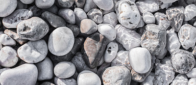 海卵石下的沙滩上有一层透明的水图片下载