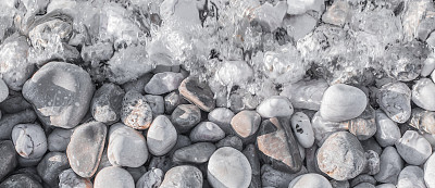 海卵石下的沙滩上有一层透明的水图片下载