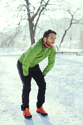 雪地上英俊的年轻跑步者。彩色的照片图片下载
