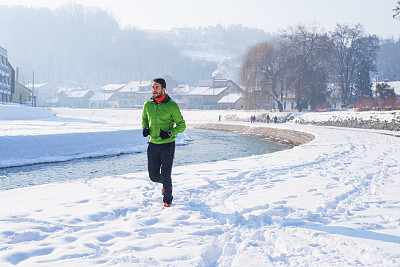 雪地上英俊的年轻跑步者。彩色的照片图片下载