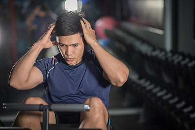 亚洲男人在健身房做仰卧起坐。图片下载