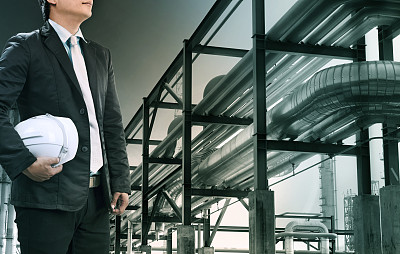 带安全帽的工程人员站在重石化工业的炼油厂，用于化石能源和石油动力的主题图片下载