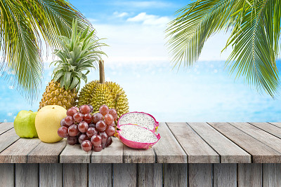 在模糊的海滩背景下，木桌上的水果。夏天的概念,图片下载