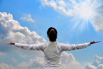 女人伸出双臂，对着天空和云彩图片下载