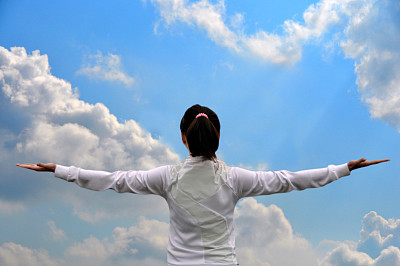 女人伸出双臂，对着天空和云彩图片下载