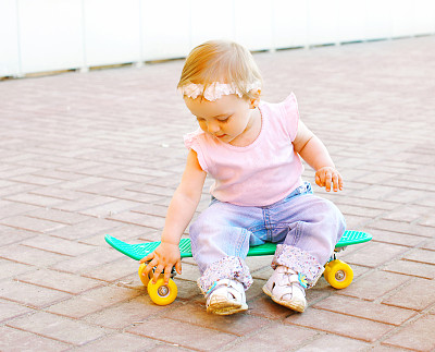 婴儿坐在城市的滑板上图片下载