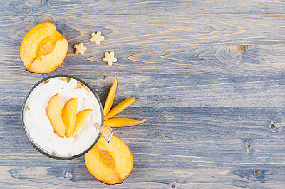 色彩缤纷的早餐配酸奶，星星玉米片，熟桃片放在蓝木板上。带有拷贝空间的装饰边框。图片下载