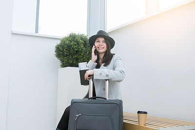 机场女商务人员在候机楼门口用智能手机等待图片下载