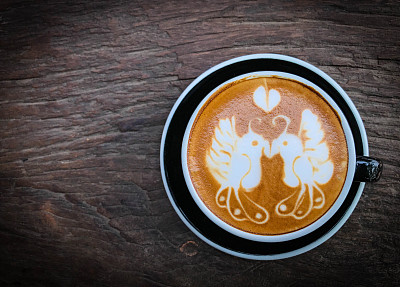 拿铁艺术咖啡设计约2鸟和心形的黑色杯在旧的木制背景图片下载