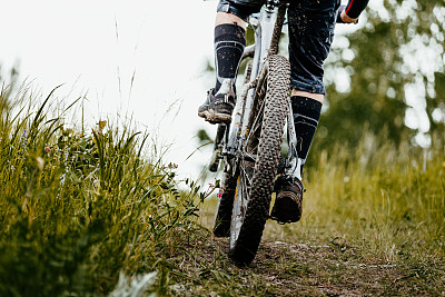 近景泥山自行车车轮和自行车的腿图片下载