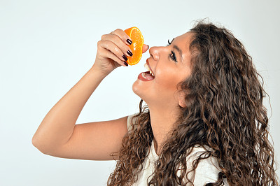 漂亮的卷发女孩吃橘子挤图片下载