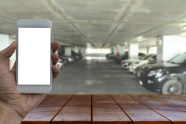 空木桌空间平台和手持智能手机与白色空白屏幕模糊停车场在商场背景的产品显示蒙太奇图片下载