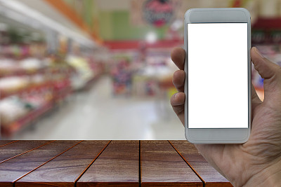 空木桌空间平台和手持智能手机的白色空白屏幕模糊超市和零售商店在购物中心的室内背景产品显示蒙太奇图片下载