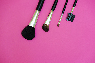 在亮粉色的背景上使用化妆刷。图片下载