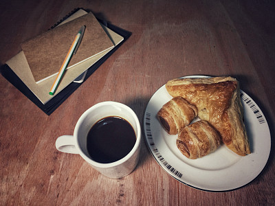 沙拉，黑咖啡，面包，书，放在复古设计的木桌上，暖色调，模糊的灯光背景图片下载