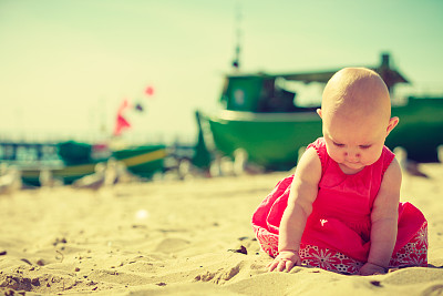 小婴儿坐在沙滩上玩耍图片下载