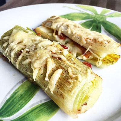 白盘子上放两颗烤韭葱。图片下载