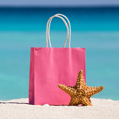 购物袋和海星在沙滩上对抗绿松石加勒比海水图片下载