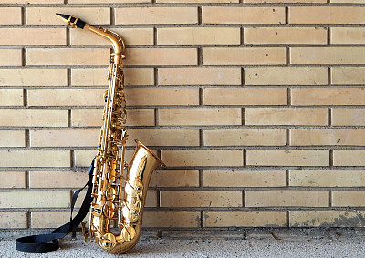 萨克斯风倚着一堵黄色的砖墙图片下载